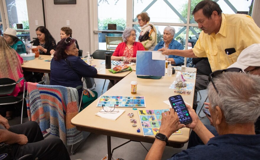Marcelino Iñiguez (right, yellow shirt) grabs his notebook filled with dozens of poems he’s written over the years during a Manitos gathering Friday, May 23, 2025, in Sacramento.