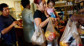 Abran Lopez (left), who was laid off from his job as a landscaper, and Angelina Martinez, who lost her construction job, receive groceries from a food co-op in Fort Lauderdale, Fla., in April 2009.