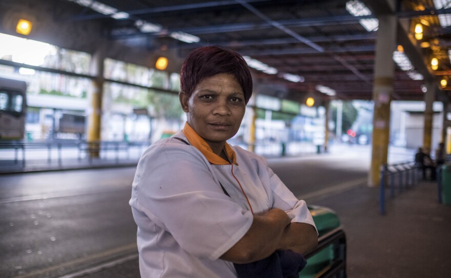 Anna Simpson, 41, who works in the kitchen of a Cape Town hospital, waits for a bus to take her home to the community called Lost City, where she lives with her husband. Many workers who keep crucial industries running live in townships and rely on public transport to get to work — putting them at risk of exposure to COVID-19.