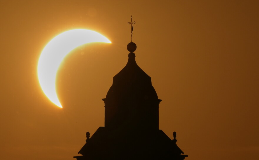 A solar eclipse is seen over a Virgin Maria church in Vidigulfo, near Pavia, northern Italy, Wednesday, Aug. 12, 2026.