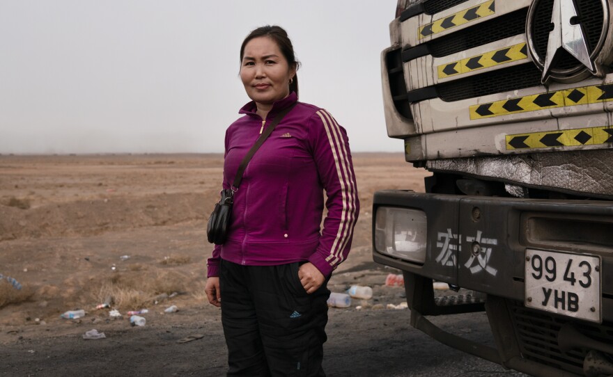 Gulnara Dariiga, 38, stands in front of her truck, a North Benz assigned to her by her Chinese employer. She performs a tea ritual in the morning, praying drivers stay safe on the road.