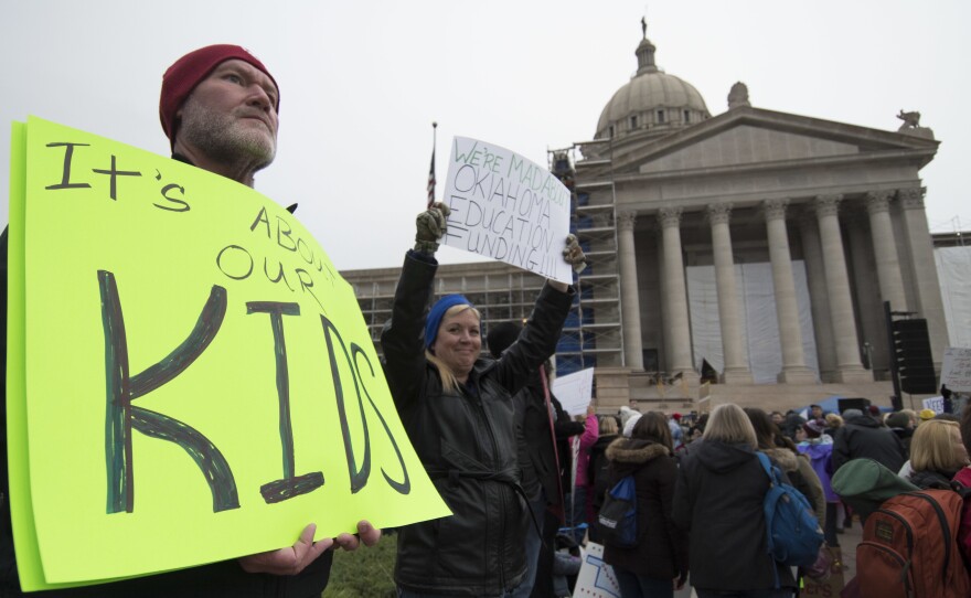 Kent Scott, a teacher from Tecumseh, Okla., holds a protest sign Monday at the state capitol in Oklahoma City. Thousands of teachers and supporters have rallied this week for more money for education.