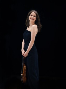 violinist Veronika Eberle is shown holding her violin against a black background