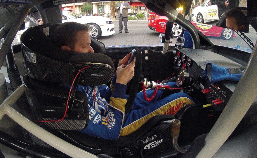 Brad Keselowski looks at his smartphone during a NASCAR champions parade in Las Vegas in November.