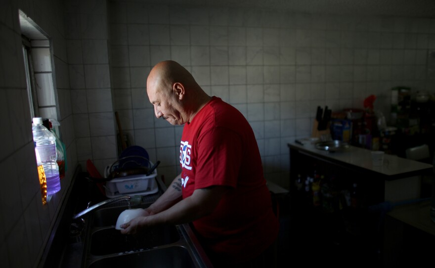 Hector Barajas washes the dishes in the Deported Veteran Support House, also known as The Bunker. Barajas has been running the shelter, seen in the bottom right photo, for about five years. At left is a collection of photos from Hector Barajas' service in the U.S. Army.