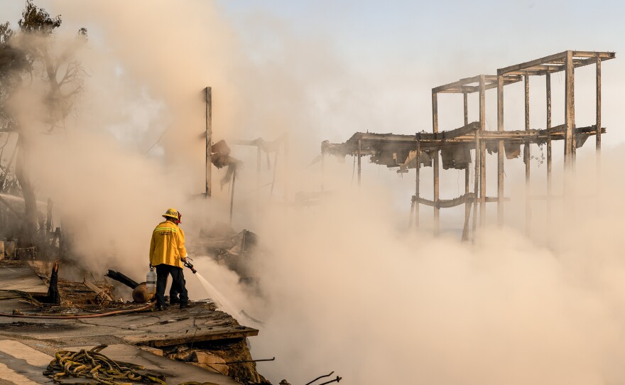 A firefighter work to put out a fire in the rubble of a home that burned down on Pacific Coast Highway near Malibu, as a result of the Palisades Fire. Jan. 9, 2025.