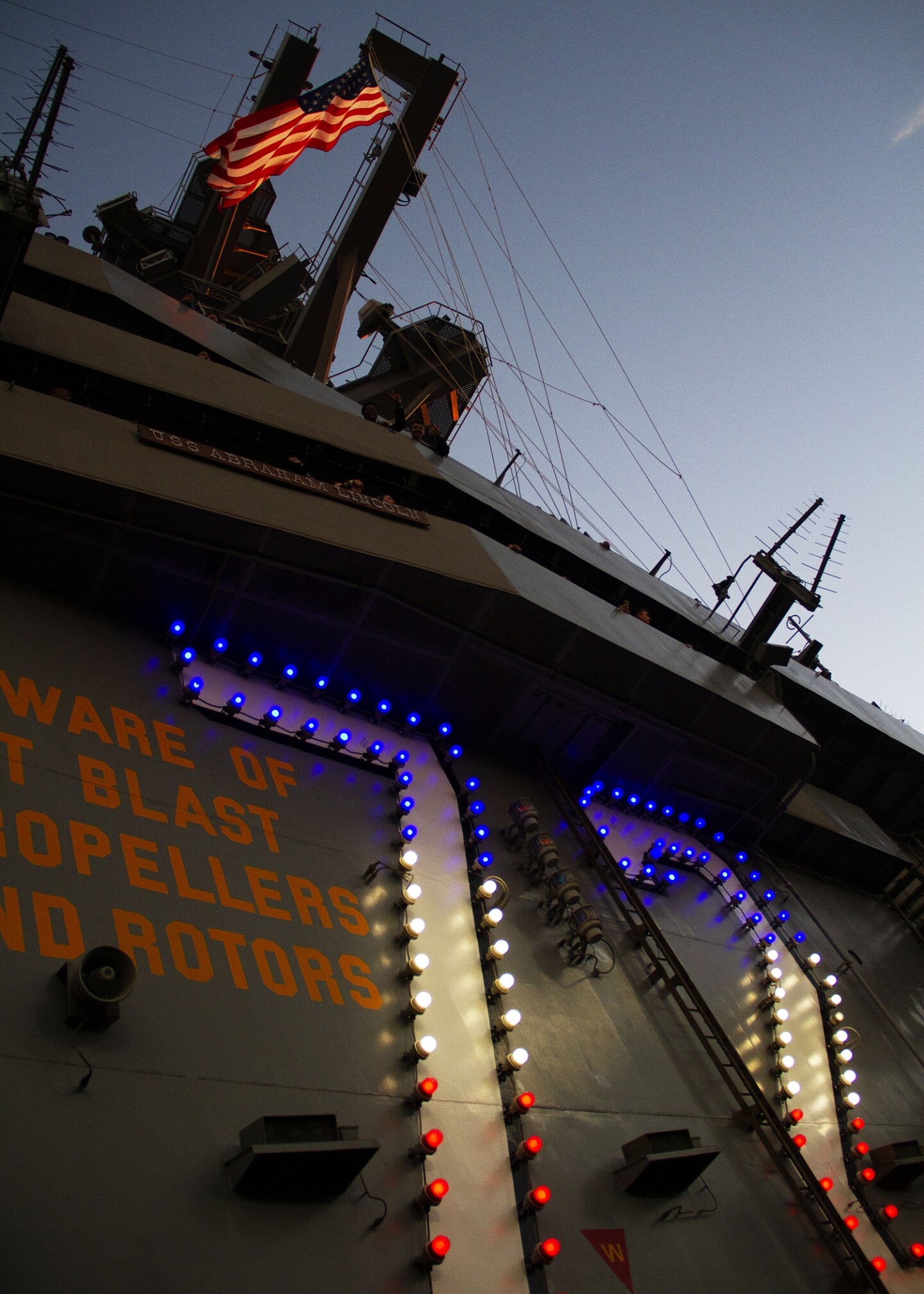 The U.S. flag waves as the sun sets aboard the USS Abraham Lincoln in San Diego on Nov. 11, 2022.
