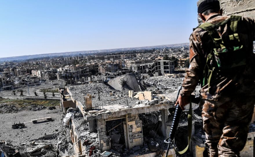 A member of the Syrian Democratic Forces walks on a building near Raqqa's stadium Monday, as they cleared the last positions on the front line in the fight against ISIS.