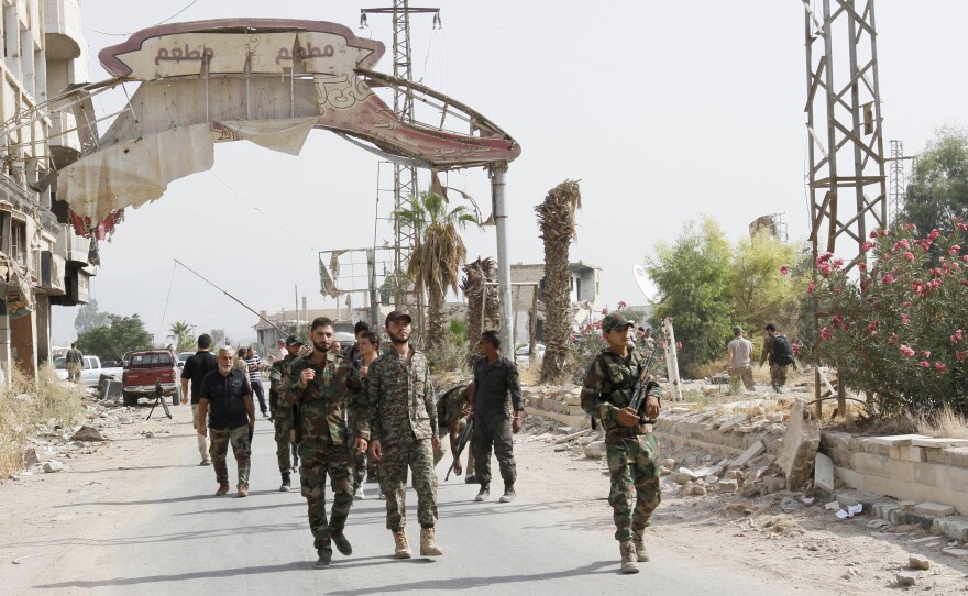 Syrian soldiers walk at the entrance of Daraya, a besieged Damascus suburb, on Friday.