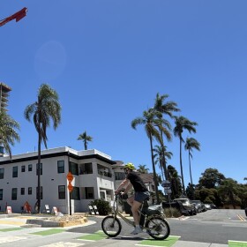 A cyclist rides by the construction site of a high-rise apartment building in Banker's Hill, July 25, 2025.