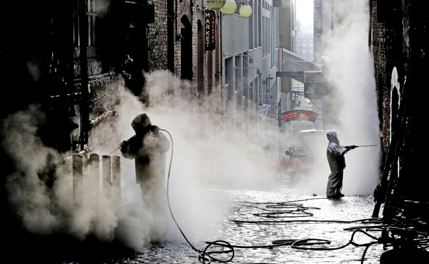 Workers use powerful steam cleaners to clean decades of gum off Seattle's famous "gum wall" on Tuesday. Tourists and locals have been sticking their used chewing gum to the wall near Pike Place Market for 20 years, leaving an estimated 1 million pieces in a kaleidoscope of colors, some stretched and pinched into messages, hearts and other designs. On Tuesday, cleaners began melting it all off.