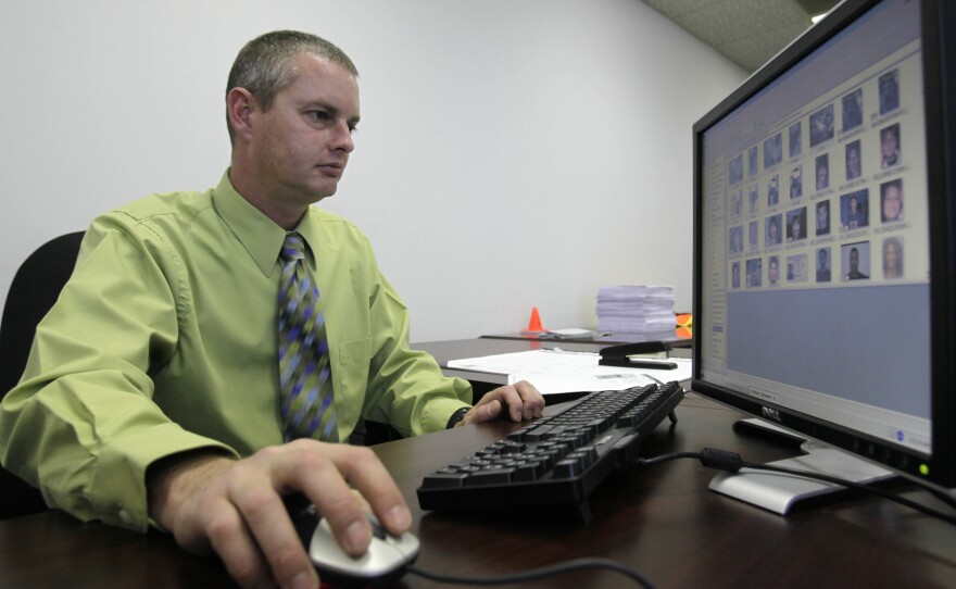 Stephen Lamm, a supervisor with the ID fraud unit of the North Carolina Department of Motor Vehicles, looks through photos in a facial recognition system in 2009 in Raleigh, N.C.