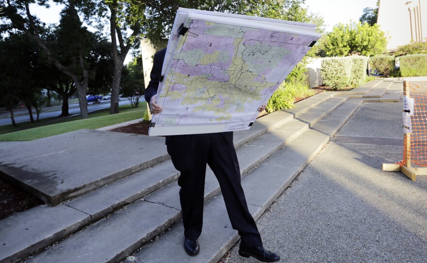 A man with a set of maps heads to a federal courthouse in San Antonio last year for a redistricting trial. Texas is one of three states with cases before the Supreme Court in redistricting.