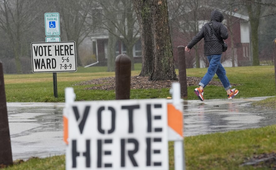 A voter braves a cold rain running to cast a ballot during the Spring election Tuesday, April 2, 2024, in Fox Point, Wis.