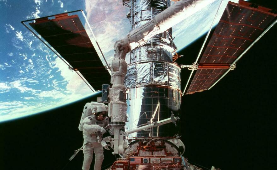 In a 1997 servicing mission, astronaut Steven Smith does a spacewalk as the telescope sits in space shuttle Discovery's cargo bay.