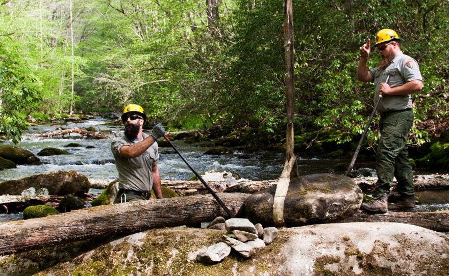 Brad Metler (left) and Mason Phillippi position a rock that will serve as an abutment for a small footbridge across the Oconaluftee River to an old cemetery in Great Smoky Mountains National Park. Both men work for the park's trail crew, which maintains more than 800-miles of trail in the park.