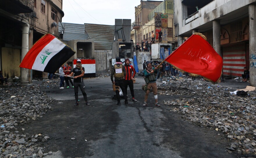 Anti-government protesters wave flags on Rasheed Street in Baghdad on Sunday.