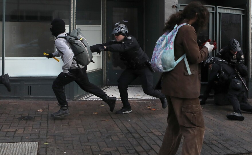 A Seattle police officer chases an anti-fascist protester during the United Against Hate rally by the Washington Three Percent in Seattle last month.
