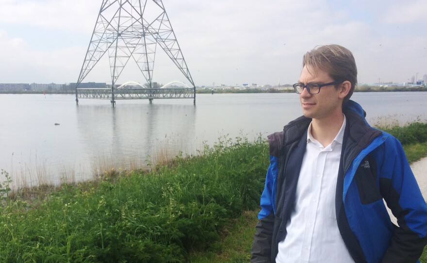 Dennis van Berkel, an attorney with Urgenda, stands on the outskirts of the city on an earthen berm. The level of the water is higher than the land on the other side of the berm.