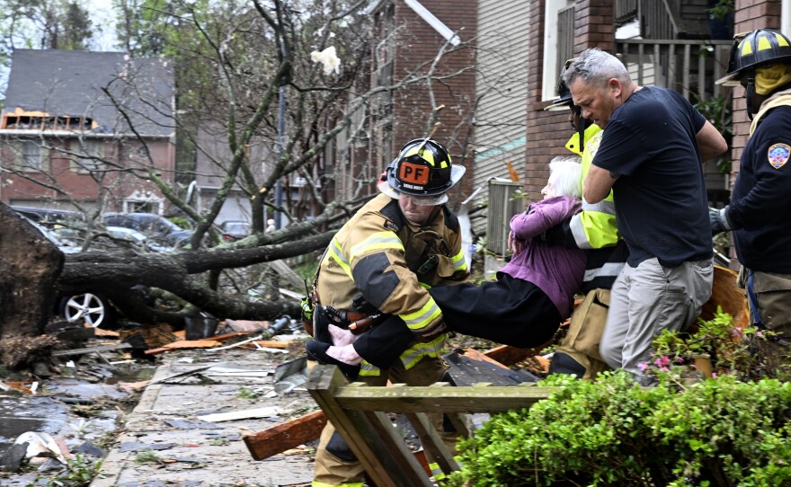 Firefighters carry a woman out of her condo after her complex was damaged by a tornado on Friday in Little Rock, Ark.