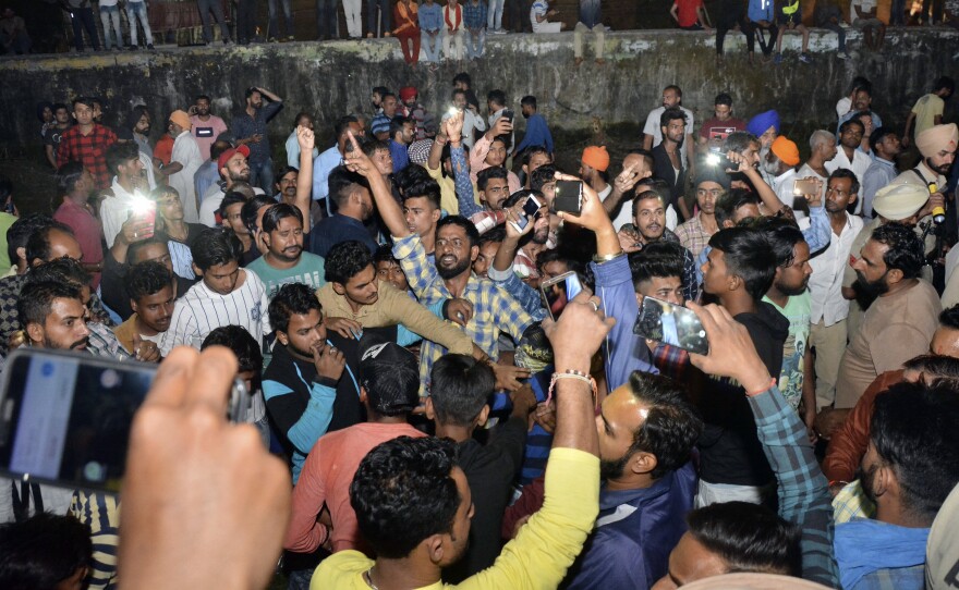 An angry crowd shouts slogans at the site of a deadly train accident on the outskirts of Amritsar, India, on Friday. One official said the local response was on par with a "war footing" as emergency workers tended to the dead and injured.