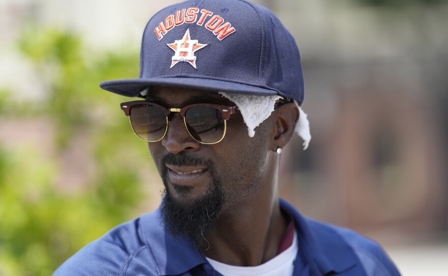 Parking lot attendant Donnay Wright wears a towel under his ball cap as he tries to keep cool in the heat outside Minute Maid Park before a baseball game between the Cincinnati Reds and Houston Astros Saturday, June 17, 2023, in Houston.