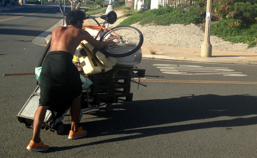 A homeless man who had been living in a large encampment in the Kakaako neighborhood of Honolulu pushes his belongings away as city officials sweep the area on Oct. 8. Honolulu city crews cleared the final section of one of the largest homeless encampments in the nation, once home to hundreds of people.