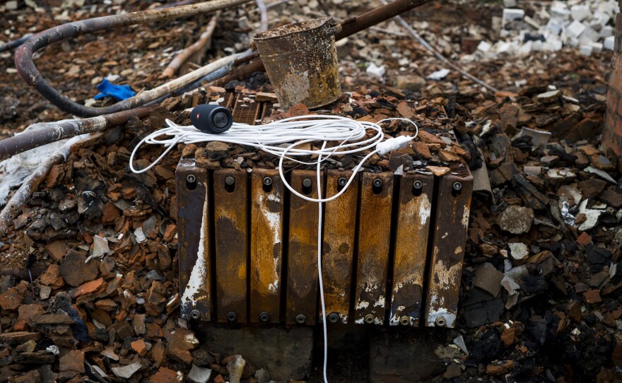 A portable speaker and an extension cord rest on a heater in the rubble of a home in Kolychivka on Oct. 1.