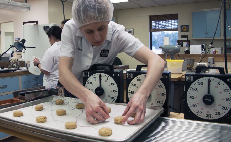 A researcher at AIB International inserts thermometers into cookie dough to monitor the baking temperature. The goal is to make sure the dough reaches the temperature needed to kill any bacteria inside.