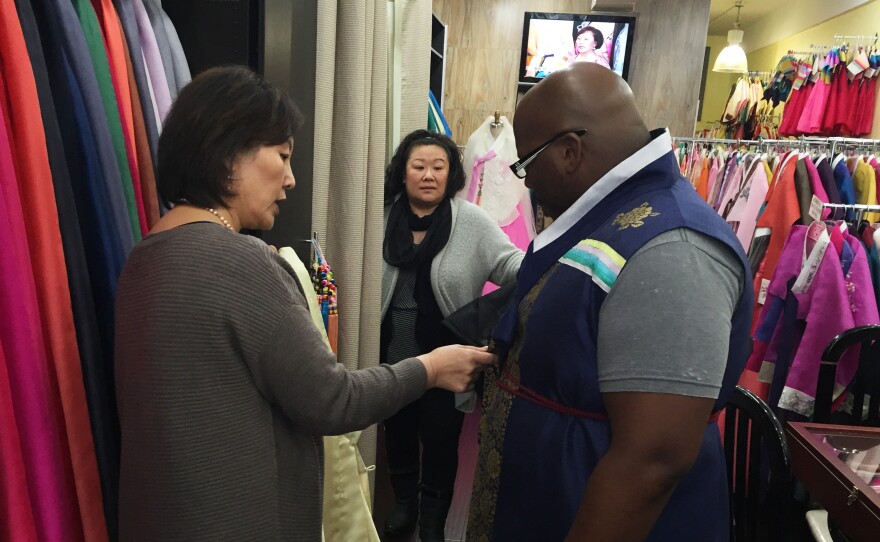 Youjung Jung measures Berris Anderson for a hanbok as his wife Lisa watches.