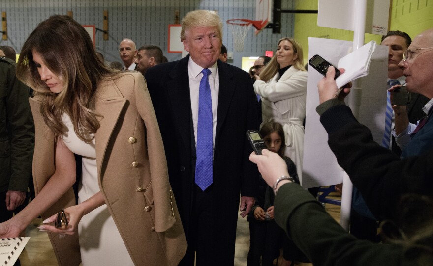 Republican presidential candidate Donald Trump, accompanied by his wife Melania, talks with reporters as he waits in line to vote at today at PS-59 in New York.