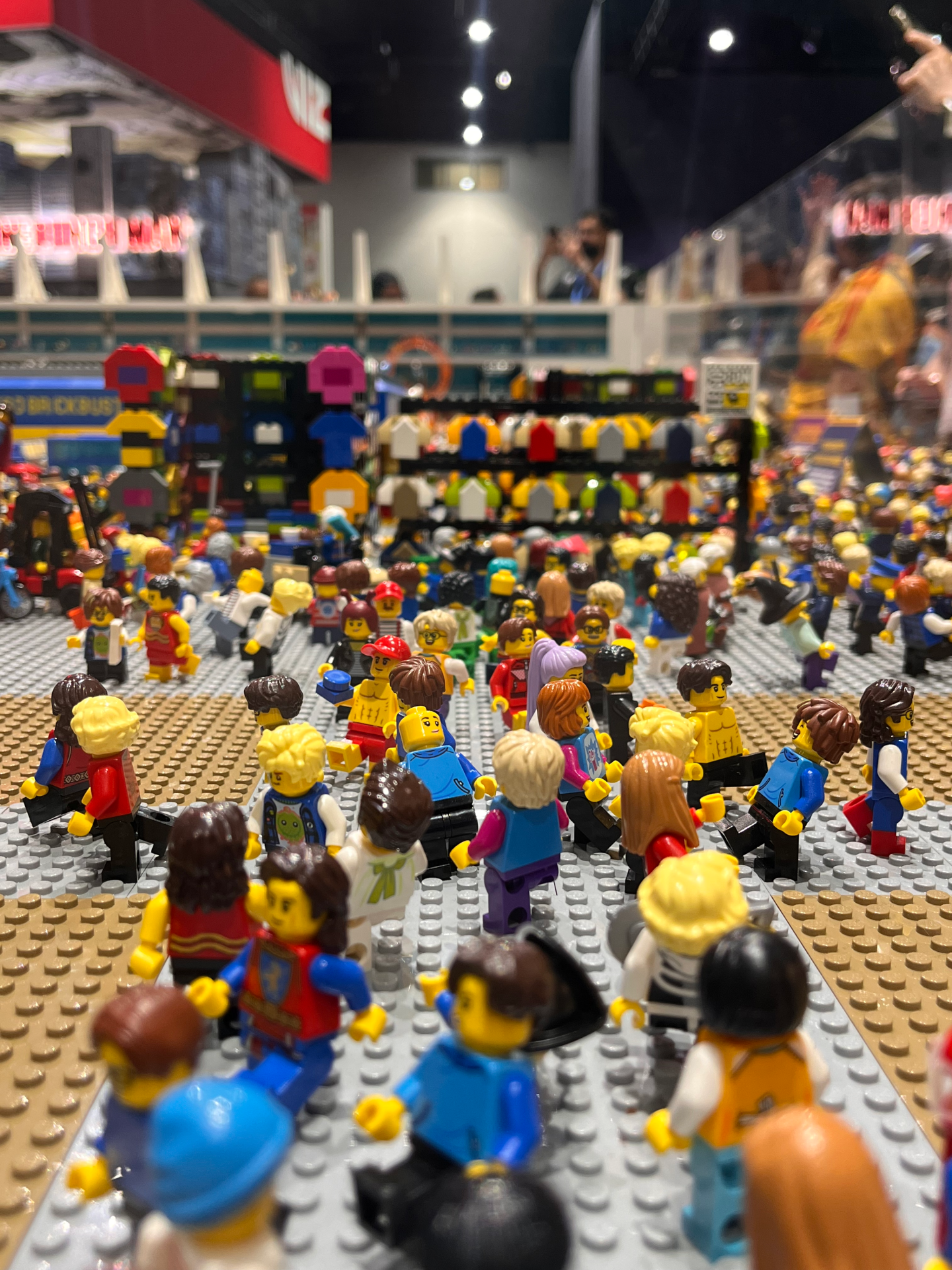 On the exhibit floor of LEGO Comic-Con, crowds of minifigs explore booths and browse T-shirts from tiny vendors. Photo taken July 25, 2025.