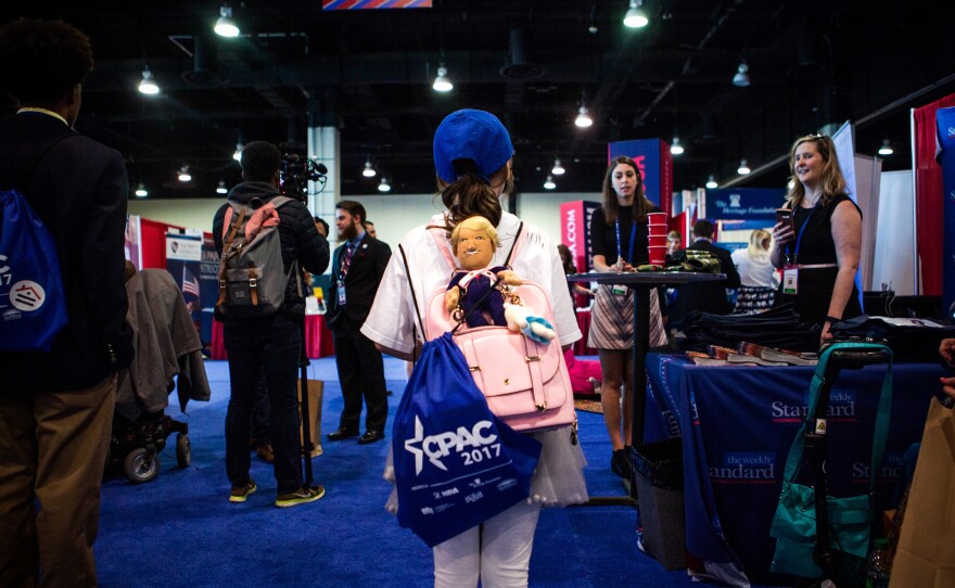 A young girl shows off her plush Trump doll in the Exhibitor Hub.