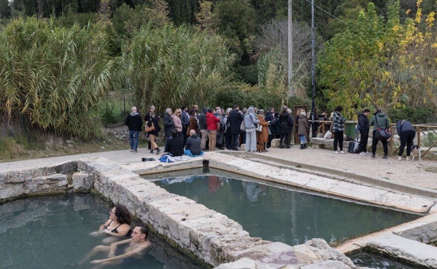 A group of tourists walk to the archaeological site at San Casciano dei Bagni, located next to a public thermal water pool, on Nov. 12.