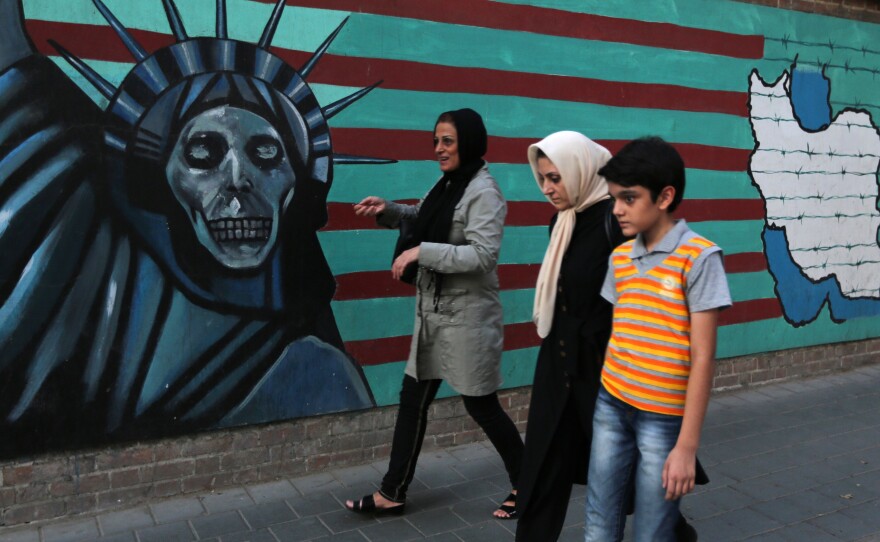 An Iranian family walks past anti-U.S. graffiti on the wall of the former U.S. embassy in Tehran on Tuesday. President Hassan Rouhani told Iranians that "all our objectives" have been met by a nuclear deal agreed upon Tuesday after talks with six world powers, including the U.S.
