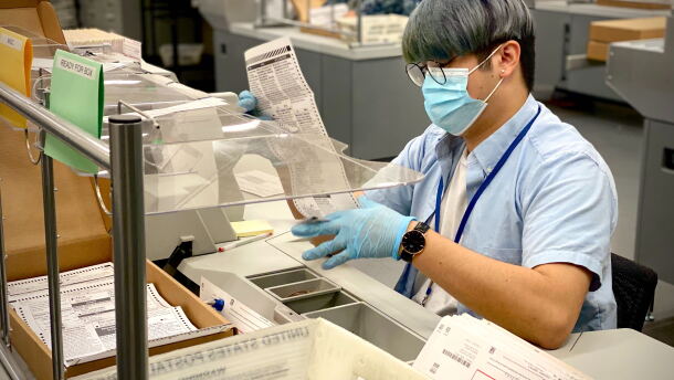 A worker at the San Diego County Registrar of Voters checks a mail-in ballot for errors in this Oct. 16, 2020 photo.