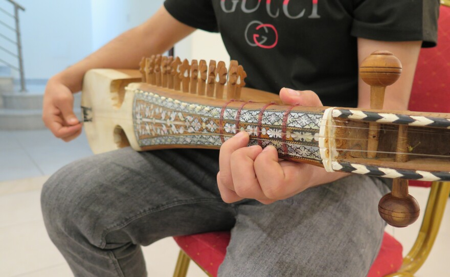 Fayaz, 19, holds his rubab. He is one of the lucky few who was able to take his own musical instrument with him when he fled Afghanistan.