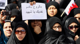 A Bahraini Shiite woman holds a sign with the words "We sacrifice our souls and blood for martyrs" written in Arabic during a funeral for men killed the day before during a violent police raid in Manama.