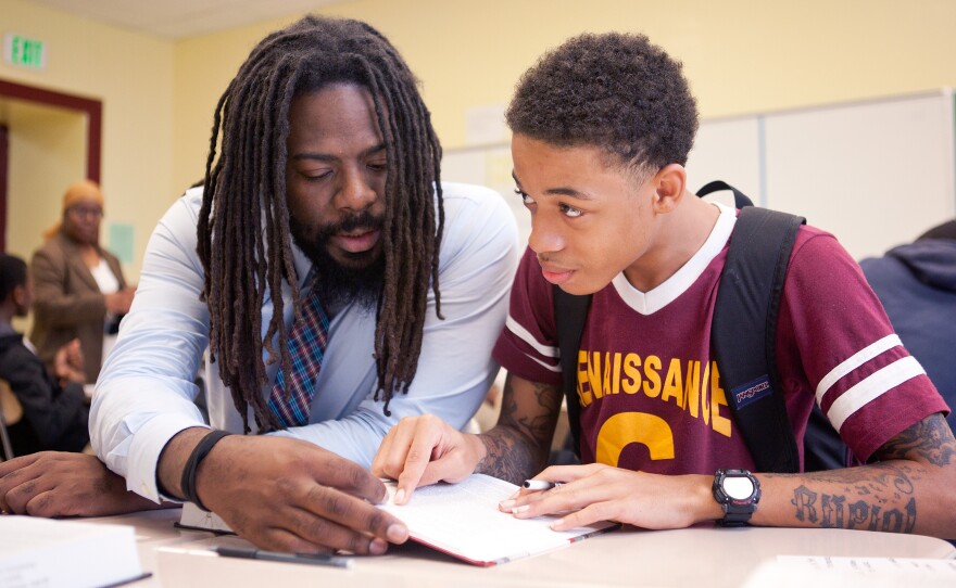 Mentor Antwon Cooper (left) helps student Julius Barne, 15, during a group activity in a history class.