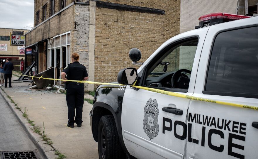 A Milwaukee police officer stands before the remains of a bar last summer, after police there faced off with protesters following the police shooting of a black man. For decades, interactions between police and people of color in the Midwestern city have been fraught, and those encounters are the subject of a new lawsuit brought by the ACLU.
