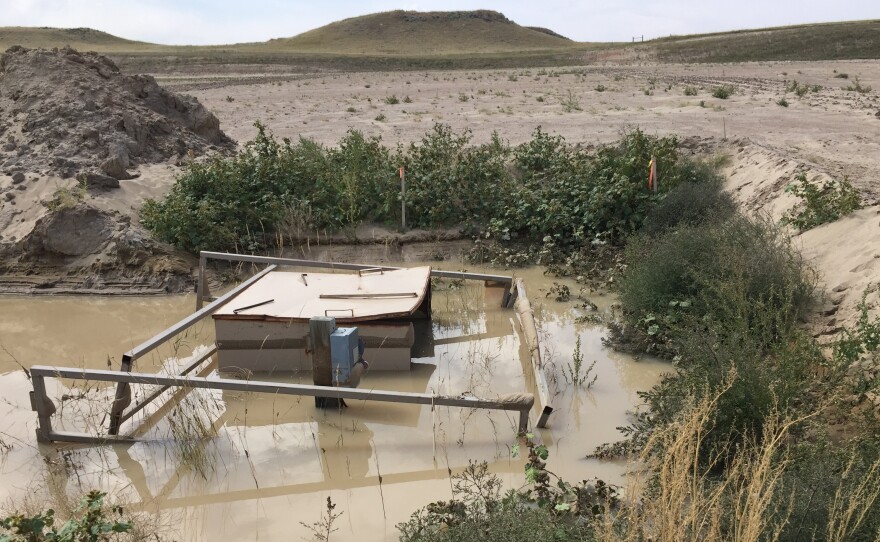 A coal-bed methane well sits abandoned in a pool of water outside Gillette, Wyo. It's more expensive than it looks to clean up.