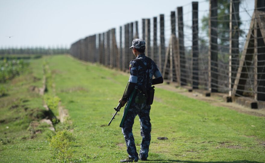 An armed Myanmar border guard patrols the fence along the river dividing Myanmar and Bangladesh in Myanmar's Rakhine state, on Oct. 15, 2016. The government says Rohingya militants carried out border raids that month that killed nearly a dozen policemen.