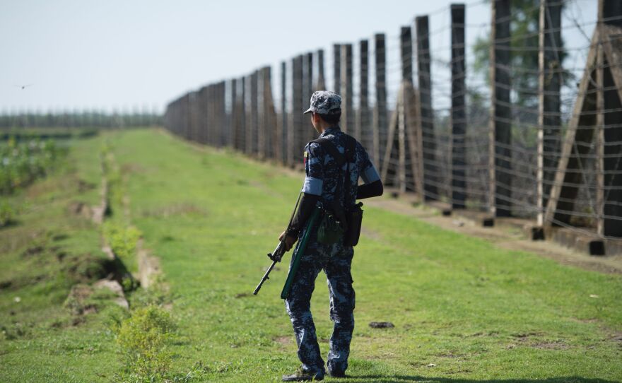 An armed Myanmar border guard patrols the fence along the river dividing Myanmar and Bangladesh in Myanmar's Rakhine state, on Oct. 15, 2016. The government says Rohingya militants carried out border raids that month that killed nearly a dozen policemen.