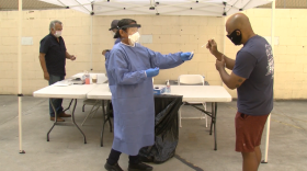  A man places his COVID-19 nasal swab into a test tube held by a public health nurse, Sept. 13, 2020.