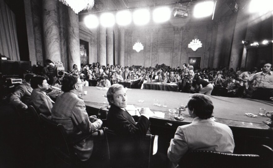 "The Dick Cavett Show" of Aug. 1, 1973 on location from the Senate Watergate Committee hearing room in Washington D.C. Dick Cavett looks over shoulder at camera; flanked by members of the committee with their backs to the camera – left to right: Senator Herman Talmadge, Senator Daniel Inouye, Senator Lowell Weicker, and Senator Howard Baker.