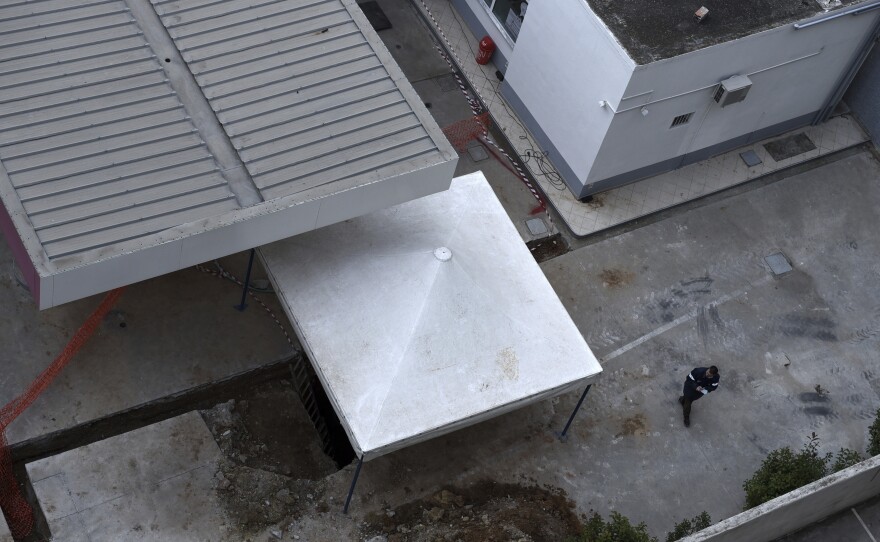 A gas station employee checks the location where an unexploded World War II-era bomb was found in Thessaloniki. This overhead shot shows just how close to the station the bomb was buried.