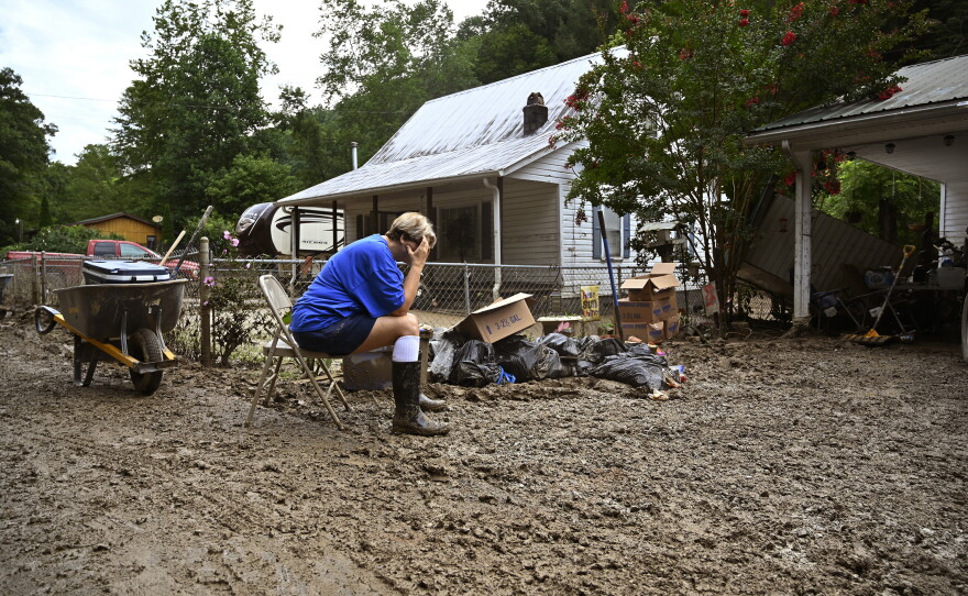 Teresa Reynolds sits exhausted as her neighbors remove debris from their flood-ravaged homes in Hindman, Ky., in July 2022. The deadly floods were caused by torrential rains. Climate change makes such record-breaking rainstorms more common in much of the United States.