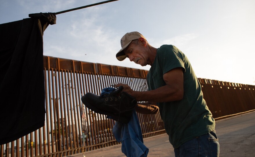Rudy Marchello cleans dust off of his boots at a farmworkers encampment in Calexico, April 6, 2020. Marchello works as an irrigator on a farm and has been staying at the encampment for a few days.