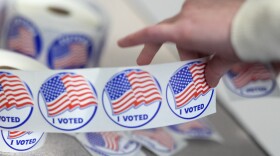 An election worker tears off "I Voted" stickers during the Virginia redistricting referendum at Fairfax Government Center, Tuesday, April 21, 2026, in Fairfax, Va.