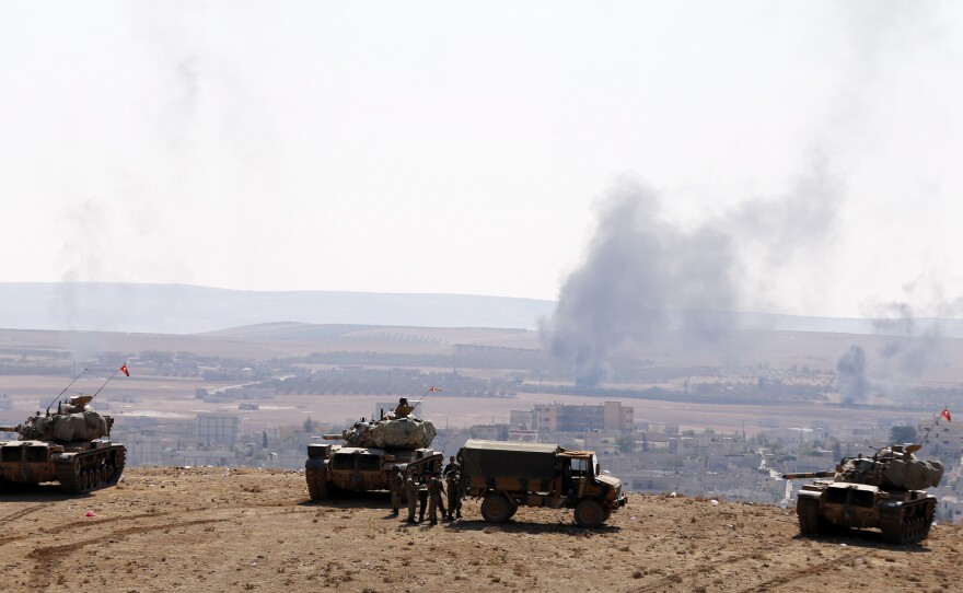Smoke rises from the Syrian town of Kobani, as Turkish army tanks take up position on the Turkish side of the border, as seen from near the Mursitpinar border crossing on the Turkish-Syrian border on Wednesday.